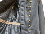 une image représentant un uniforme bleu à boutons dorés et une veste noire
