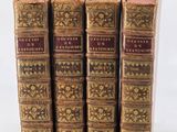 three old books sitting on top of each other on a white surface
