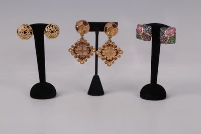 three pairs of earrings on a black stand