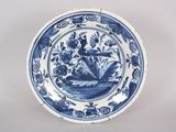 une vieille assiette bleue et blanche représentant une femme sur un bateau