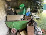 a green wheelbarrow full of junk in the yard