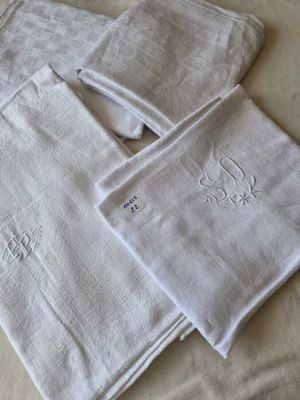 three white towels with embroidered monograms on them on a bed