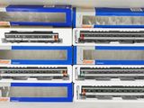 six trains miniatures sont rangés dans des boîtes posées sur une surface blanche