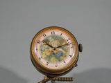 une petite horloge posée sur un trépied