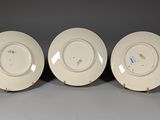 three white plates with designs on them sitting on a gray surface