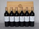 six bottles of wine are lined up in front of a wooden box