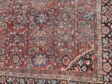 an antique persian rug is displayed on a wooden floor