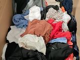 a cardboard box filled with clothes and clothes on the floor