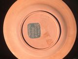 a brown plate with writing on it sitting on a black surface