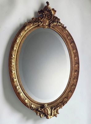 a gold mirror hanging on the wall above a sink