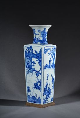 un vase bleu et blanc posé sur un support en bois