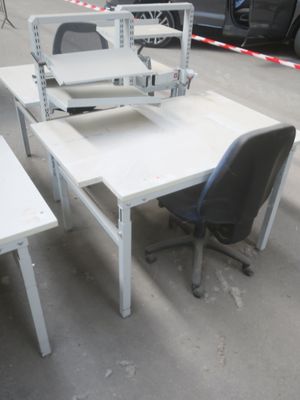 un bureau blanc sur lequel se trouve un ordinateur et une chaise noire