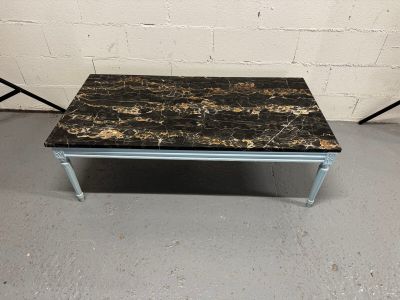 une table basse au plateau en marbre et aux pieds en métal dans une pièce