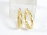 une paire de boucles d'oreilles créoles dorées présentées dans un présentoir en acrylique transparent