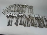 many spoons and forks laid out on a table
