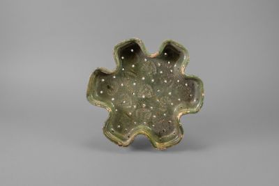 an image of a small green bowl with holes in the center