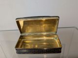 a small metal box on display on a glass table