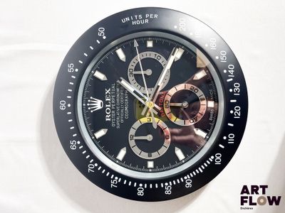 une montre noire et dorée posée sur une surface blanche