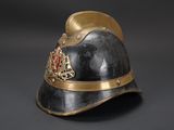 an old helmet with a gold crown on it sitting on a black surface