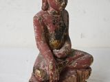 an old statue of a buddha sitting on top of a tree stump