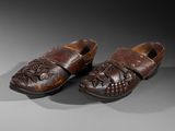 pair of wooden shoes with leather soles on a grey surface