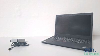 un ordinateur portable posé sur une table et auquel est relié un chargeur