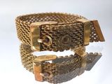 gros plan d'un bracelet en or sur une surface blanche