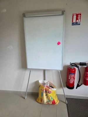 un tableau blanc posé sur un support, dans un coin de la pièce