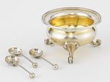 un bol en argent avec des cuillères et un repose-cuillères posé sur une table
