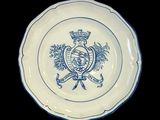 une assiette bleue et blanche sur laquelle figure un blason