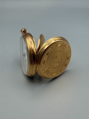 a gold pocket watch sitting on a white surface