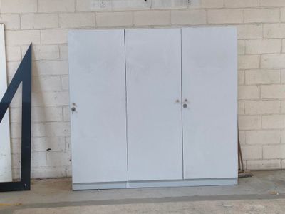 une armoire blanche placée à côté d'un miroir dans une pièce
