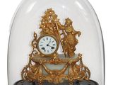 une horloge en or sous un dôme de verre sur une table