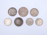 six different british coins are arranged in a row on a white surface