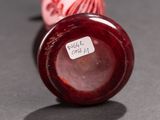 a red vase sitting on a table with a sticker on it