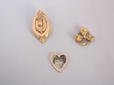 trois broches en or représentant une femme à l'intérieur d'un cœur