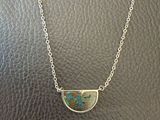 un collier en argent orné d'une pierre turquoise en forme de demi-cercle