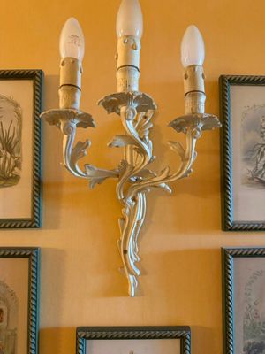 pictures on the wall above a chandelier with three candles
