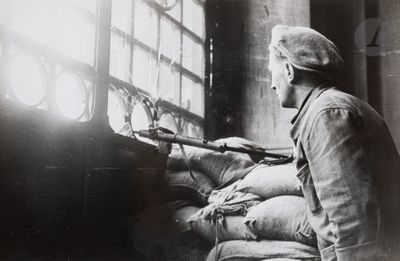 black and white photo of a man sitting in a chair with a gun