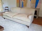 a white couch in a living room with a painting on the wall behind it