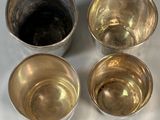 three silver cups sitting next to each other on a white surface