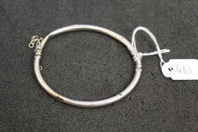 a close up of a silver bracelet with a tag attached to it