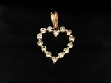 a gold heart shaped pendant with green crystals on a black background