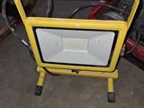 a yellow flood light sitting on a stand in a garage