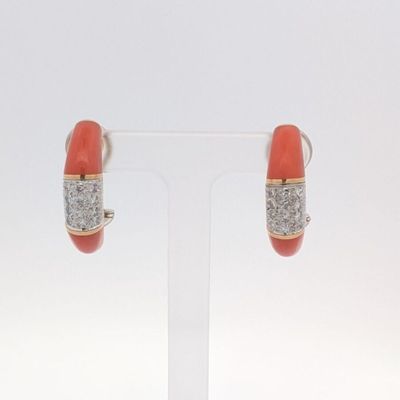 une paire de boucles d'oreilles en corail et diamants, présentée sur un présentoir transparent