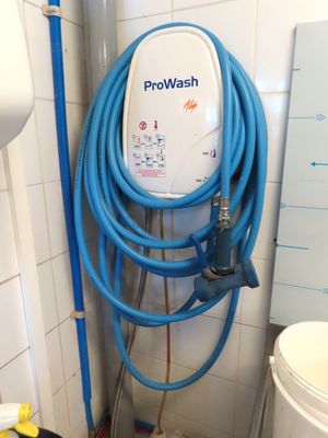 un tuyau bleu raccordé à des toilettes blanches dans une salle de bains