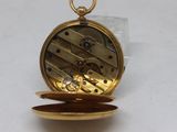 a gold pocket watch that is open on a white surface
