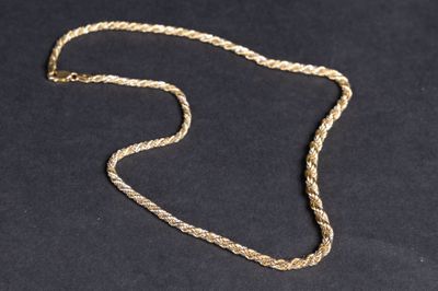 gros plan d'un collier en or sur une surface noire