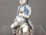 une figurine représentant un homme assis sur un panier