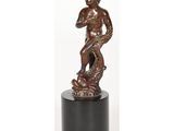 une statue en bronze représentant un garçon tenant un poisson, posée sur un socle